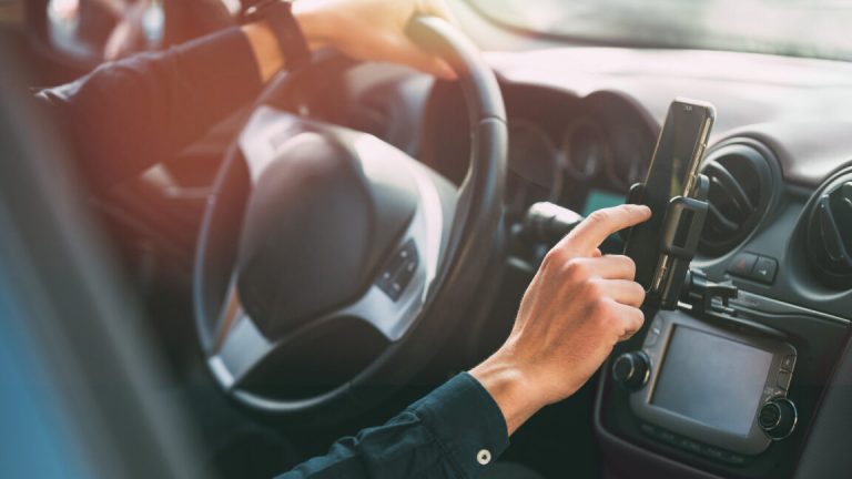 Male hand using smartphone while driving