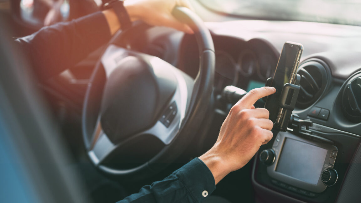 Male hand using smartphone while driving
