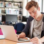 Male,Student,Working,At,Laptop,In,College,Library