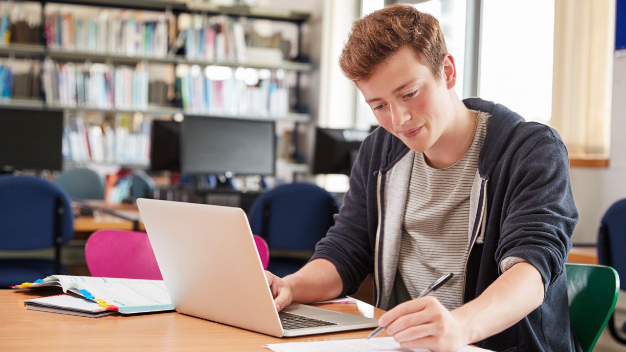 Male,Student,Working,At,Laptop,In,College,Library