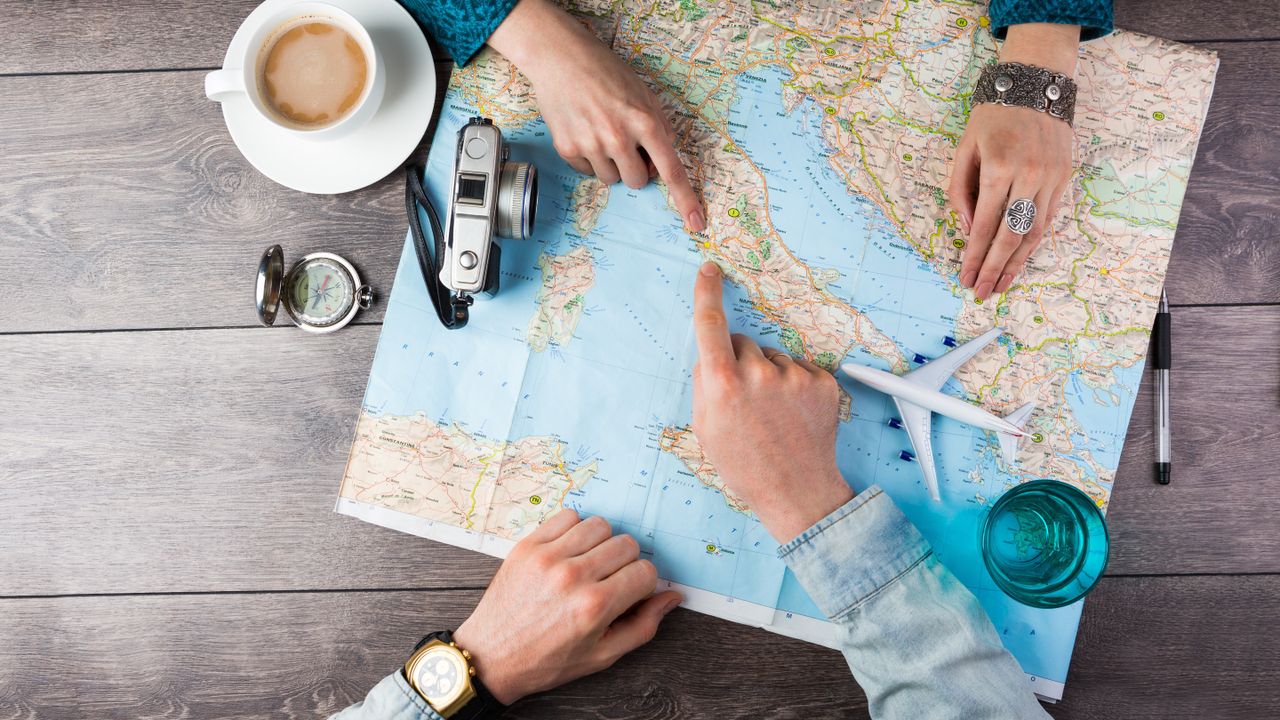 Young,Couple,Planning,Honeymoon,Vacation,Trip,With,Map.,Top,View.