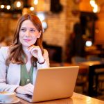 Woman working remotely in a cafe with laptop and coffee